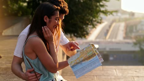 happy loving couple walking outdoors at the street holding map talking