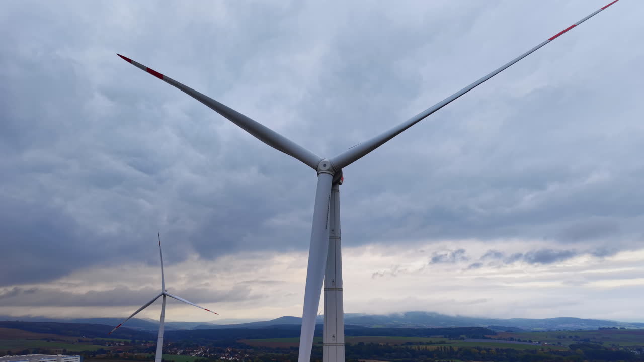 Drone shot, view of wind turbine against cloudy sky. Sunset in fields at wind farm, aerial video