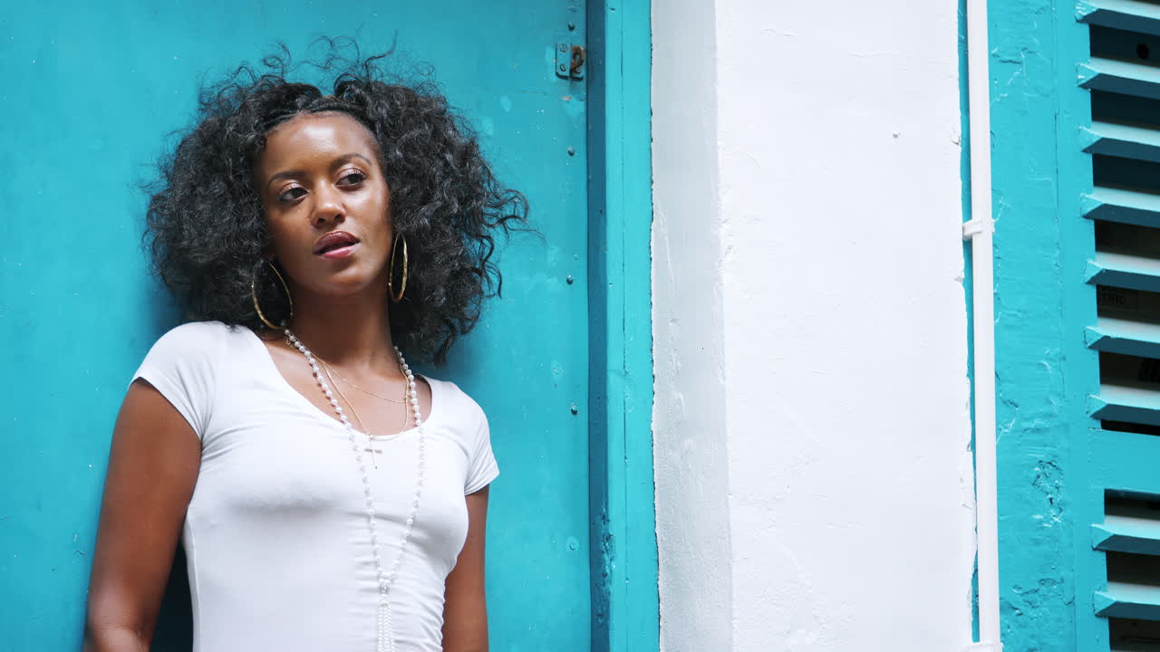 Jovem mulher negra elegante em pé ao ar livre em uma porta, da cintura para cima