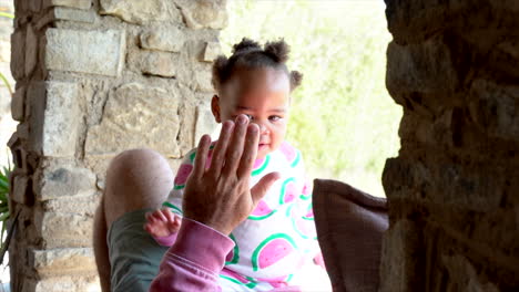 baby toddler sitting on her dad while the are playing