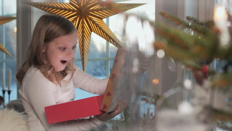 a blonde girl opens a magic light box with much happiness