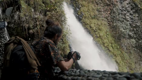 Male-Traveler-Looking-At-His-Camera-Near-Pailon-del-Diablo-Waterfall-In-Baños-de-Agua-Santa,-Ecuador---medium