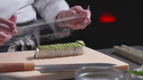 a static shot captures a finished sushi roll being rolled and wrapped, showcasing the final touch in sushi preparation. perfect for culinary, sushi-making, and food presentation content.
