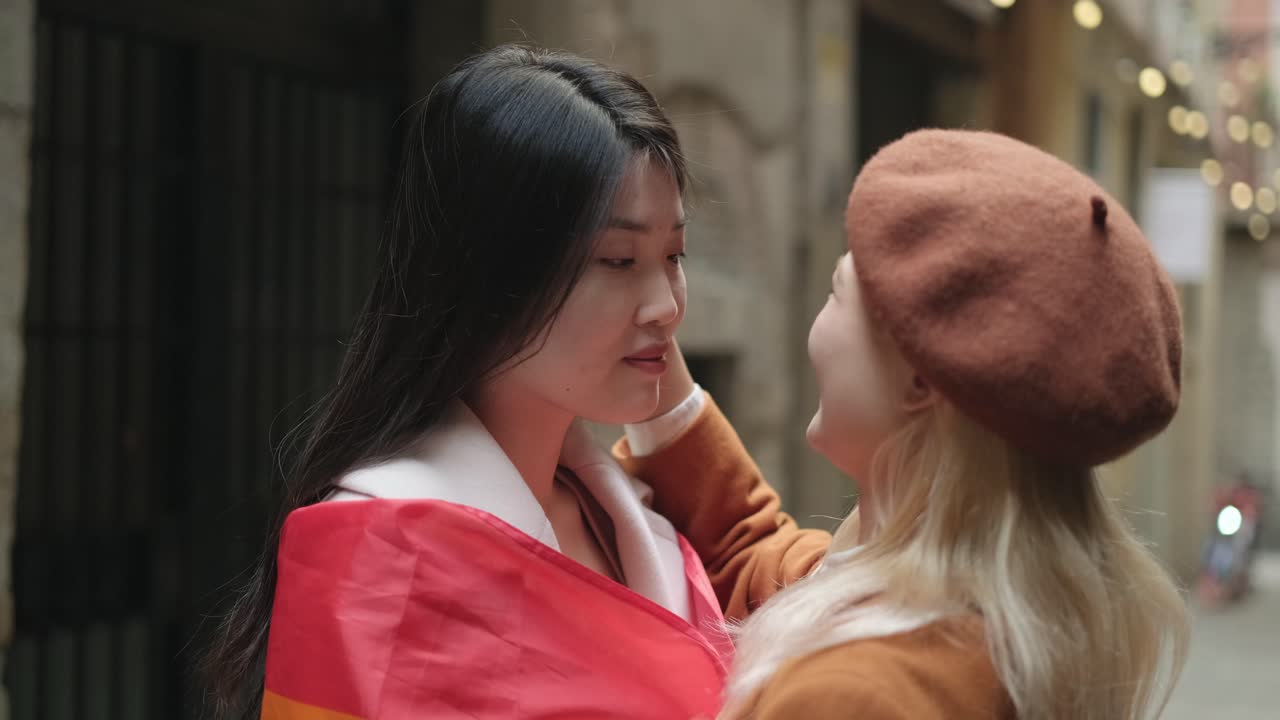 Lesbian couple with pride flag in a city street