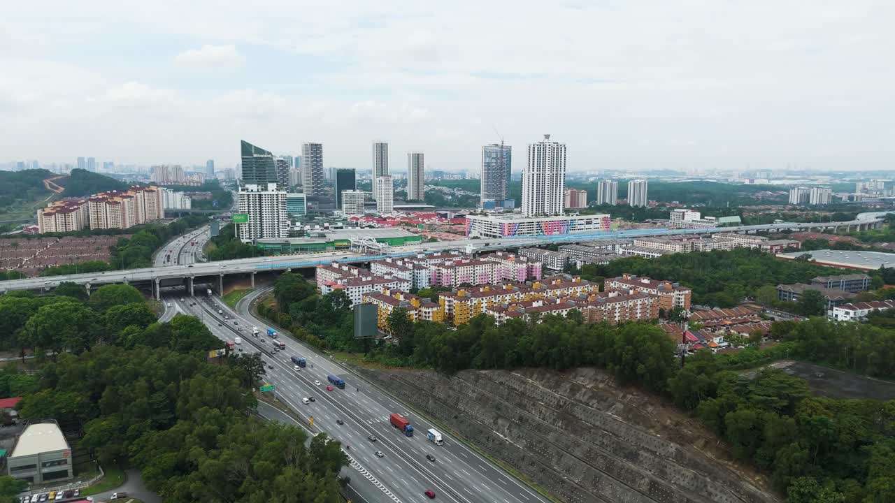 Aerial: cityscape of Petaling Jaya with traffic on a highway during the day in the state of Selangor, Malaysia, jib up drone shot