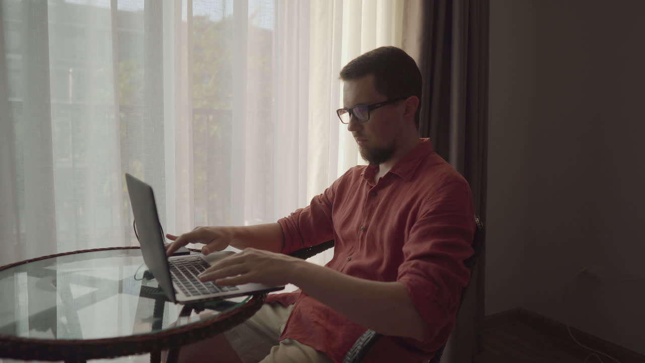 hombre trabajando en una computadora portátil por la ventana