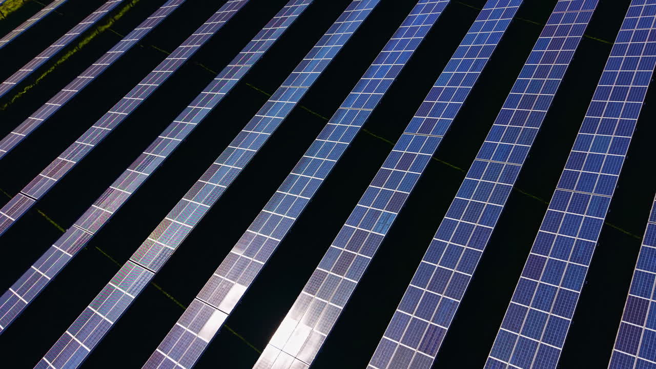 Pannelli solari allineati in file su un grande campo sotto un cielo terso di giorno, che mostrano la tecnologia dell'energia rinnovabile