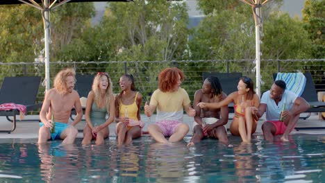 Happy-diverse-friends-with-drinks-talking-at-pool-in-slow-motion