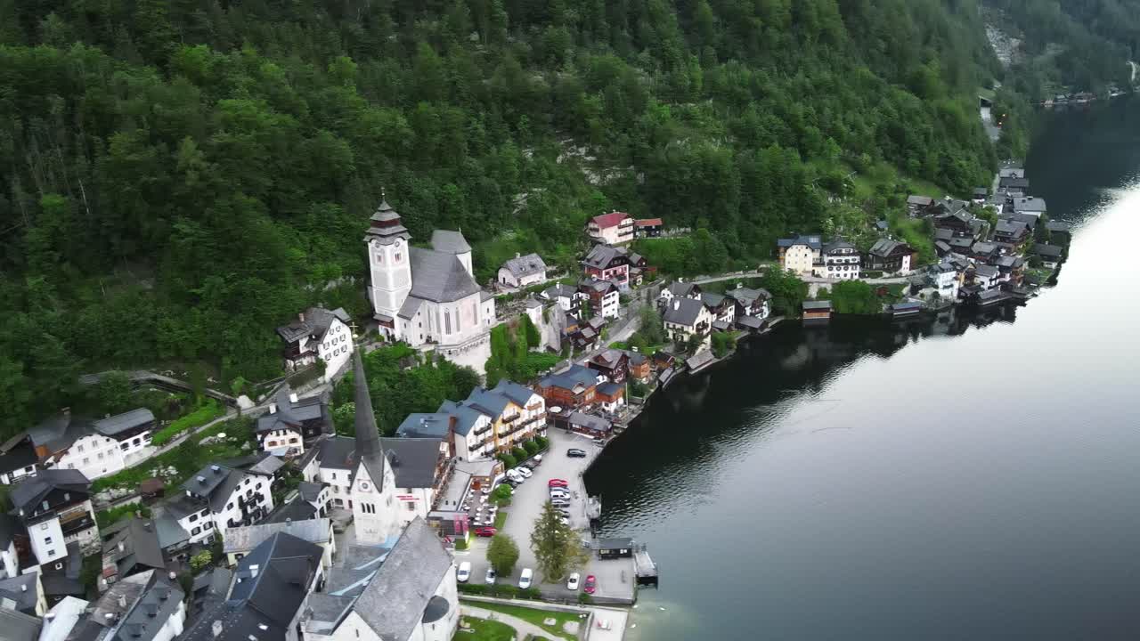 Hallstatt, en landsby i Østrig ved Hallstätter See i Salzkammergut-alperne. Dronebillede af historiske huse, kirketårne, skovklædte skråninger og roligt vand i dagslys.