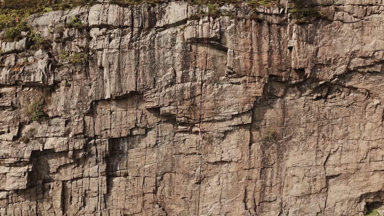 mujer escalando una pared de roca en noruega, vista aérea