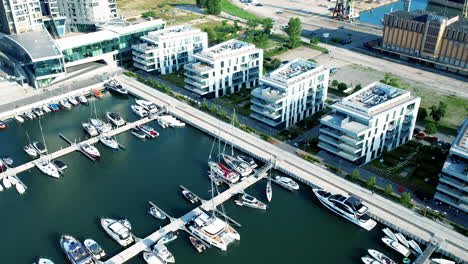 aerial birds eye shot of modern buildings at marina of gdynia city during sunny day - orbit shot