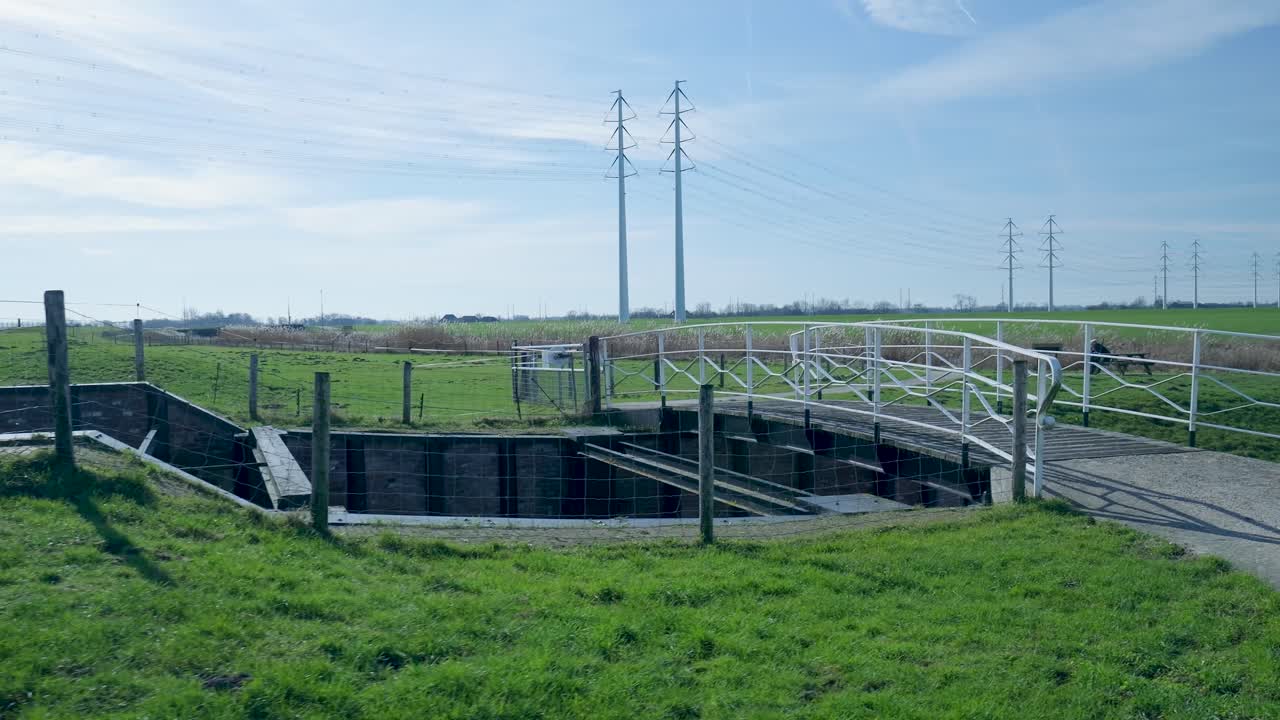 Pan Shot of Rural Landscape with Bridge, Canal, and Electricity Pylons
