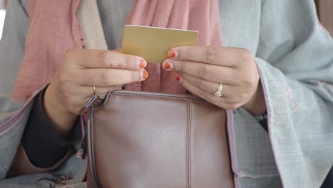 a person's hands retrieving a credit card from a purse