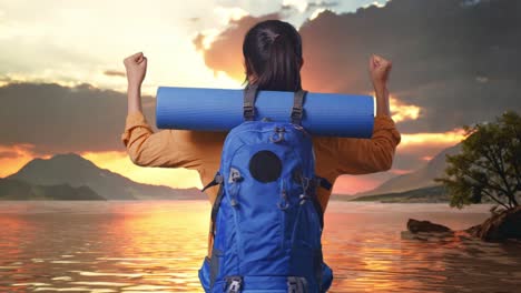 vista trasera de una excursionista femenina con mochila de montañismo gritando meta celebrando el éxito mientras estaba de pie en un lago durante el atardecer