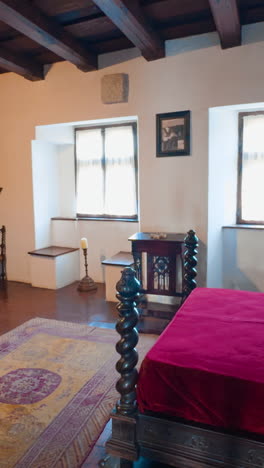 spacious bedroom in the old medieval castle of bran, brasov, transylvania, romania. antique furniture and wooden ceiling in the interior. vertical video