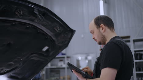 utilizando una tableta digital para un diagnóstico de automóviles. mecánico utilizando una tableta en el servicio de garaje de reparación. software de diagnóstico en una computadora avanzada.
