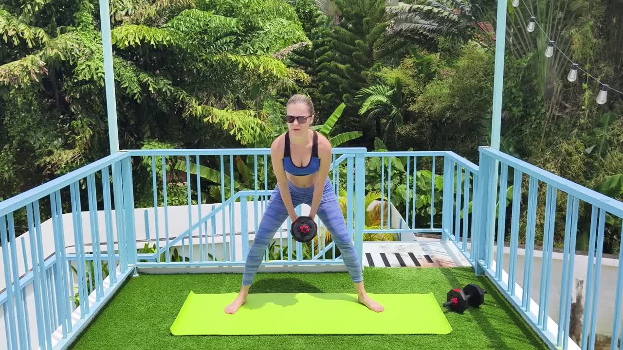 mujer realizando sentadillas con manivelas al aire libre