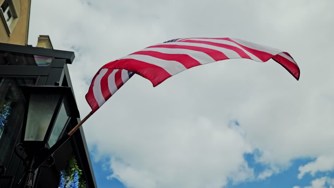 Slow motion shot of United States flag waving against cloudy sky background