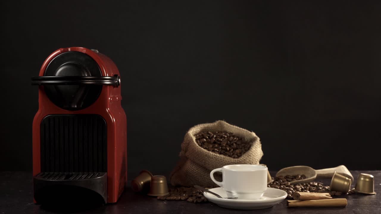 Hånd der placerer kaffekop fra rød maskine med bønner