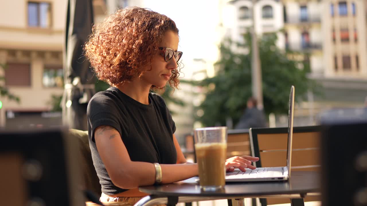 Woman working on laptop at outdoor cafe
