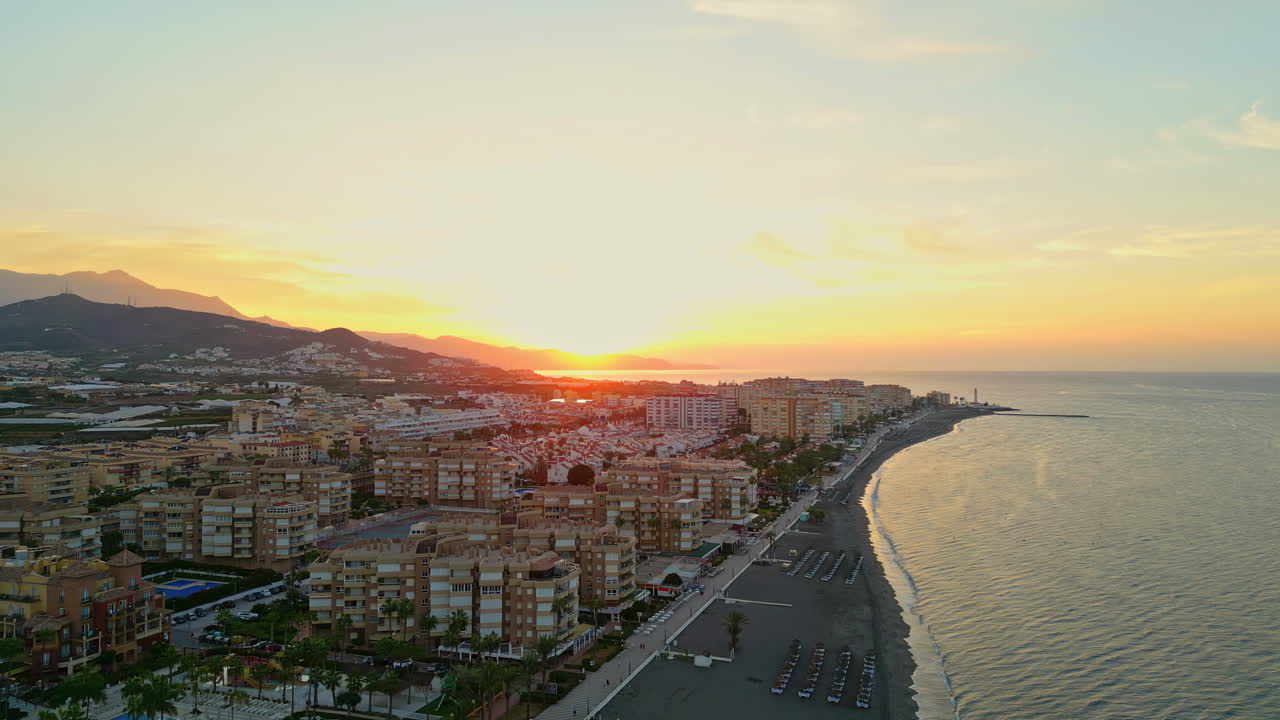 panorámico atardecer naranja dorado aéreo, resplandor vespertino grabado por drone en la playa, málaga, españa