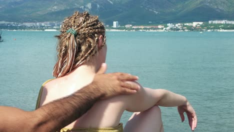 mujer poniéndose protector solar en la espalda en la playa