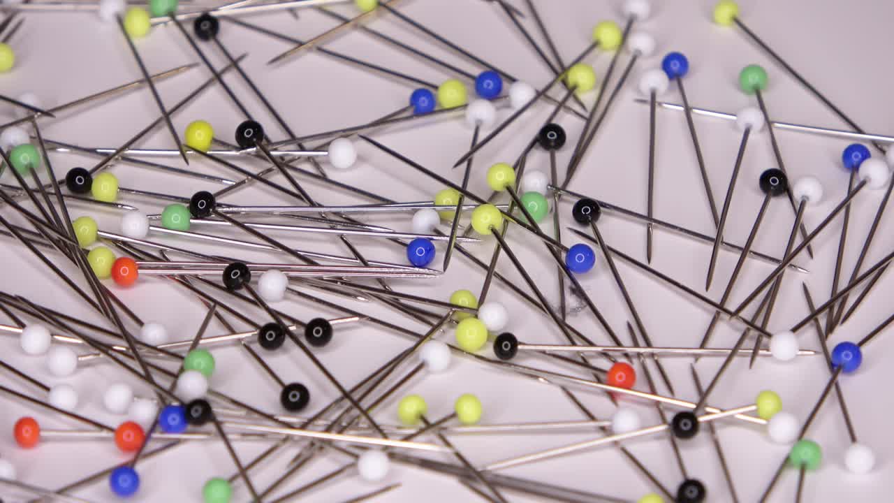 회전하는 색 배경에 다채로운 유리 머리를 가진 많은 핀의 루프 영상을 촬영할 수 있습니다.