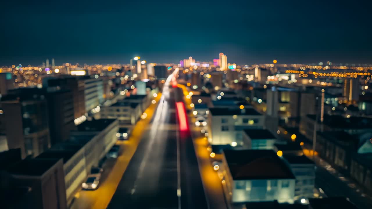 Opening aerial shot capturing traffic on avenue white headlight and red taillight trails at night
