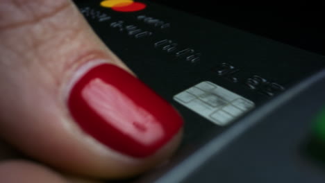 una mujer poniendo una tarjeta de crédito en la terminal postal. una mujer usando una tarjeta de débito para comprar.