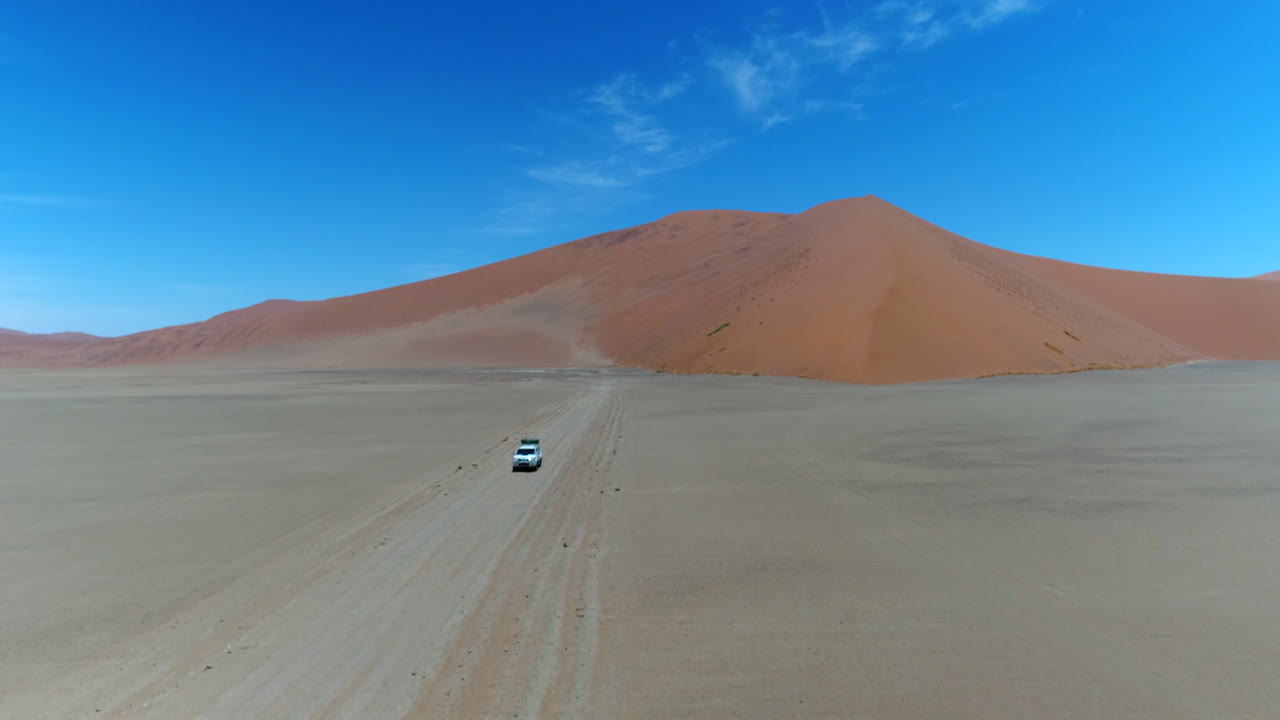 AWD Jeep with roof tent passing on a sandy road nearby Sesriem in Namibia.