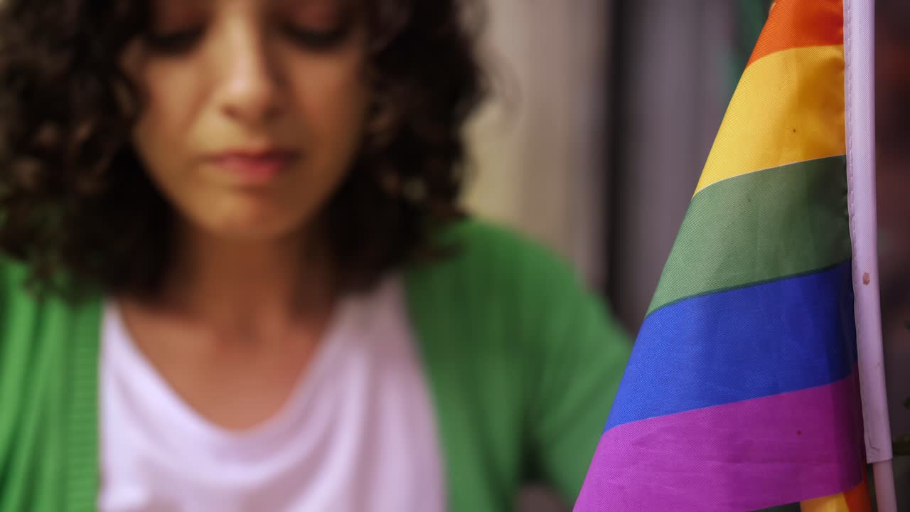 Woman Drinking Coffee Next to a Rainbow Pride Flag