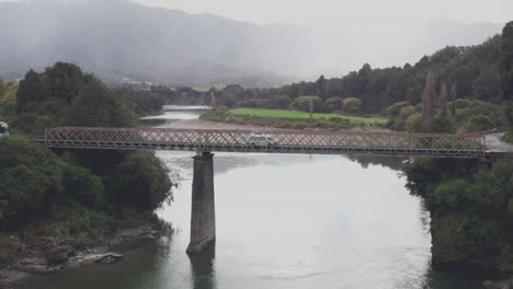 aerial drone shot of a camper van crossing the iron bridge over the buller river in new zealands south island