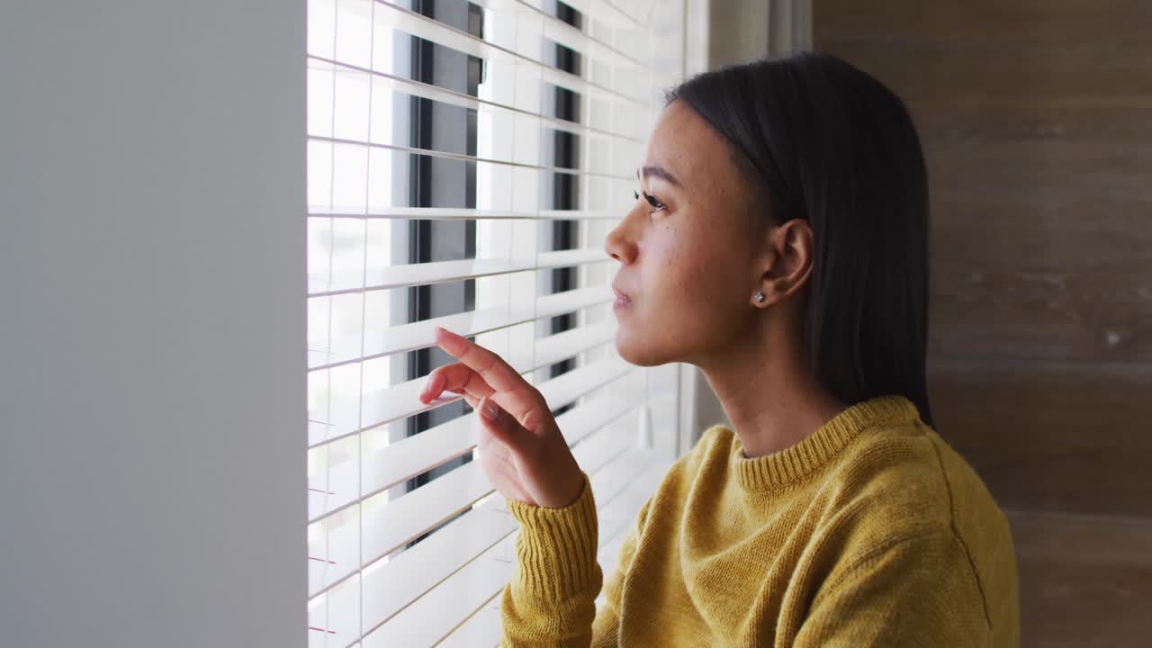 Mixed race woman standing and looking through a window