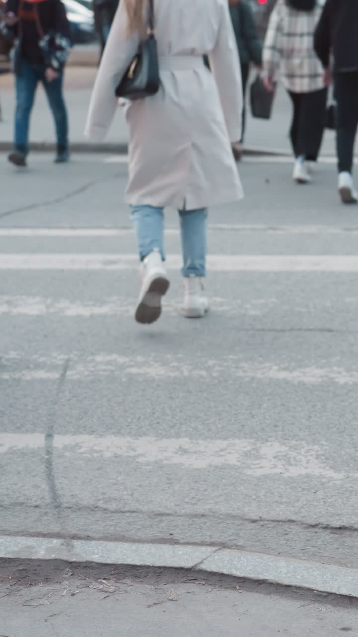 A city view featuring pedestrians walking across the street, and wearing different footwear and movement on the pavement