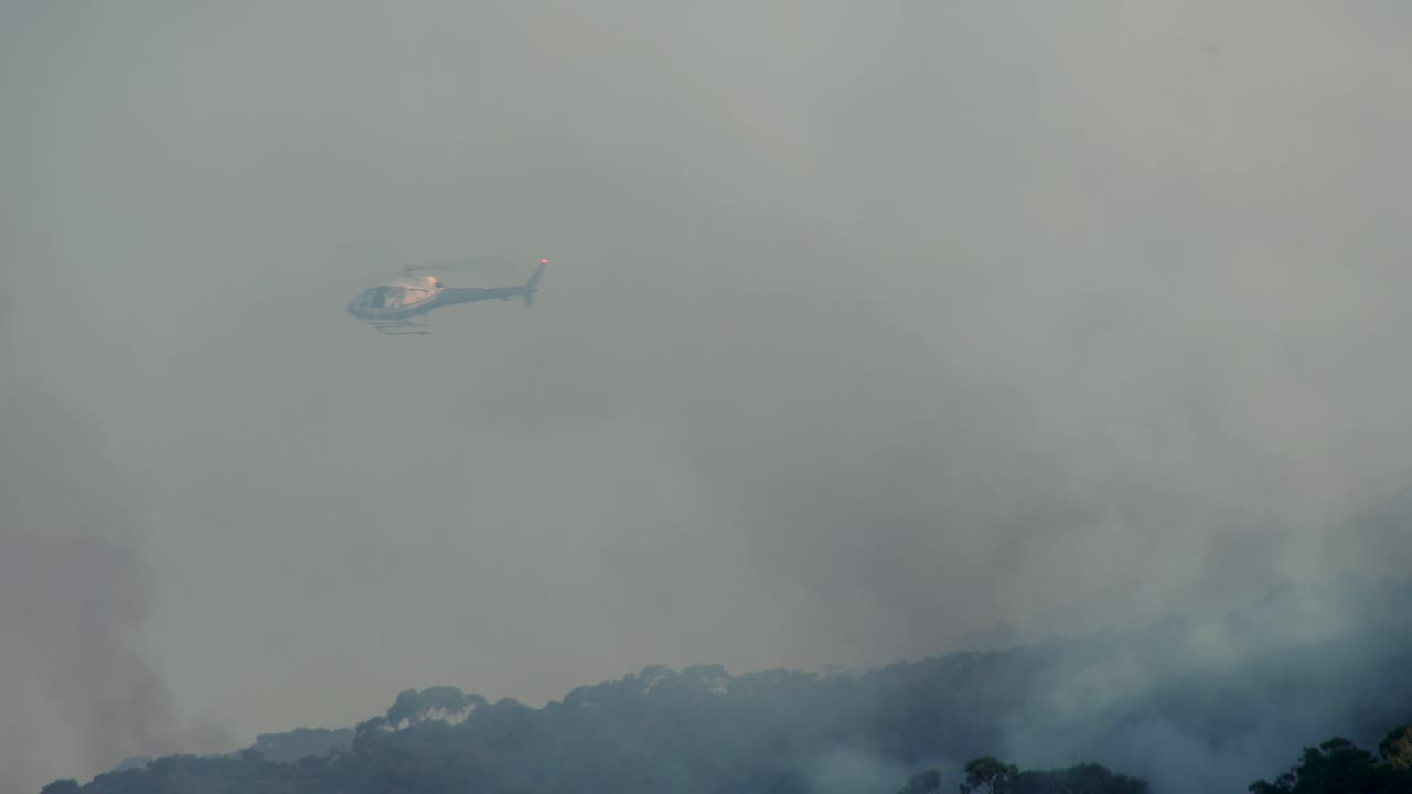 Imágenes de acción de helicóptero sobre fuego y humo. Metraje 4K de El Niño que captura quemas controladas, extinción de incendios, humo y rescates en helicóptero. 29 de mayo de 2023 Sídney, Australia