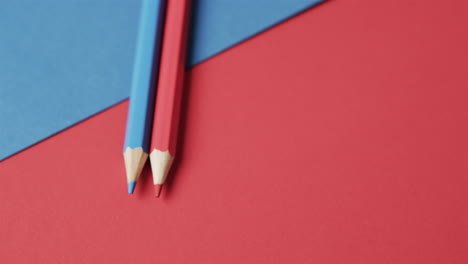 primer plano de lápices de colores azules y rojos con espacio de copia en fondo rojo y azul, en cámara lenta