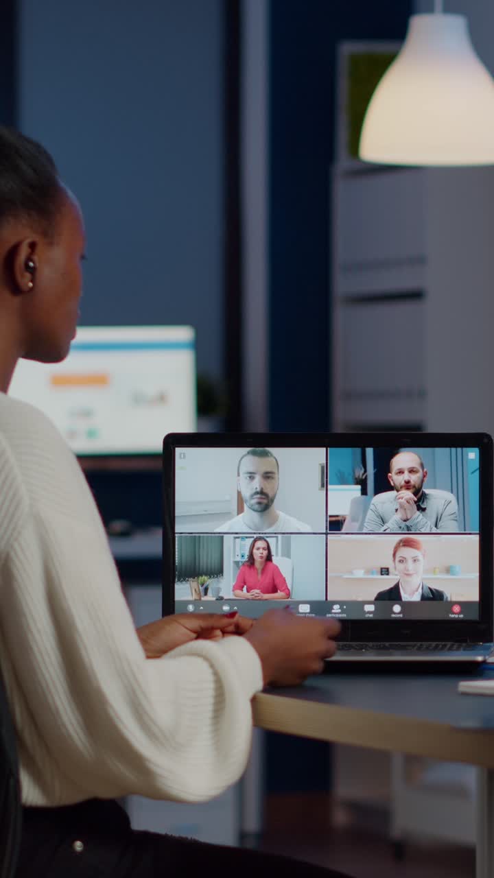 Vertical video African employee working overtime from business office late at night discussing