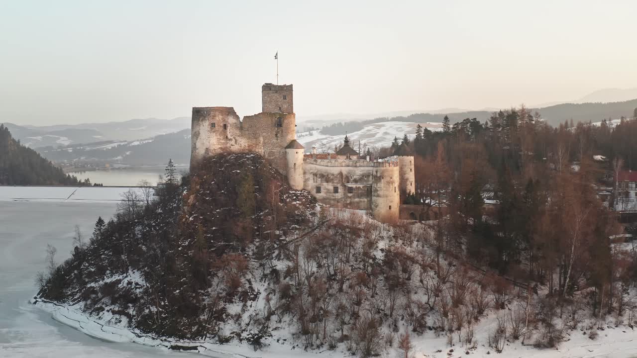 идиллический замок ниедзица в сумерках на вершине холма у замерзшего озера чорштын, аэрофотосъемка