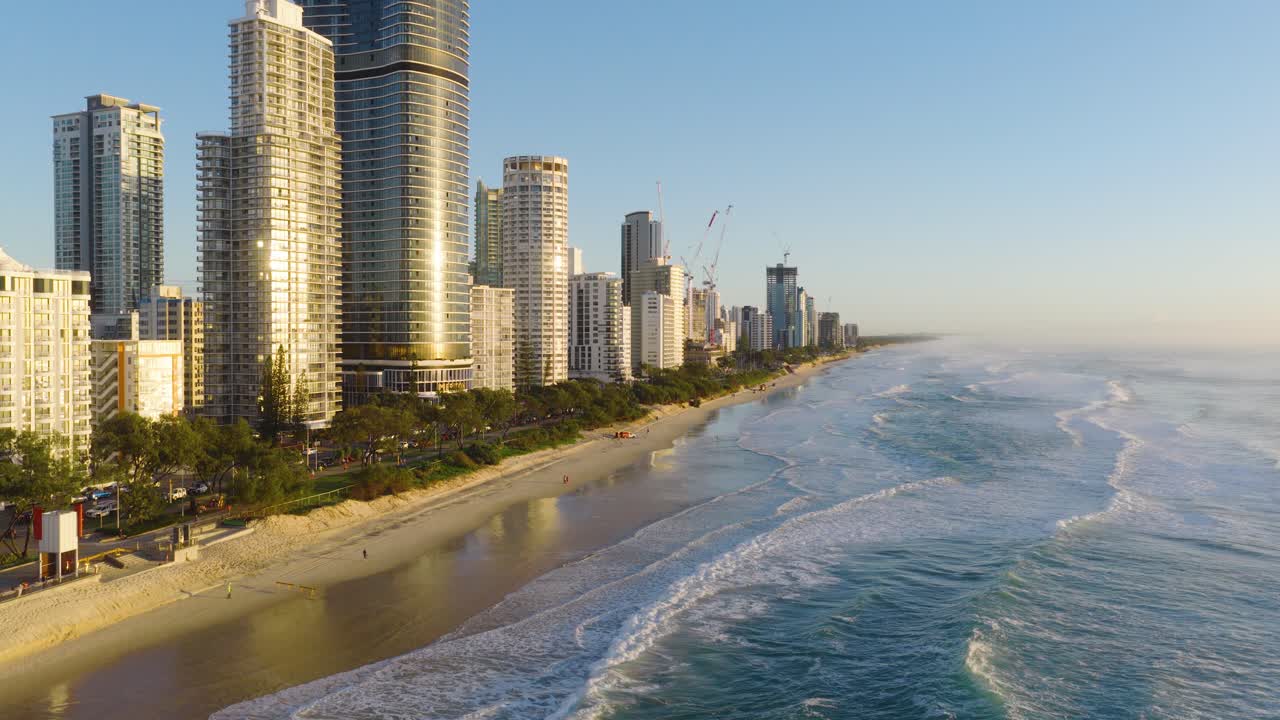Aerial view of Gold Coast's skyline and beach during golden hour, showcasing serene ocean waves and towering buildings