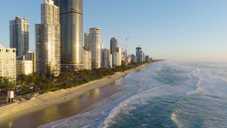 aerial view of gold coast's skyline and beach during golden hour, showcasing serene ocean waves and towering buildings