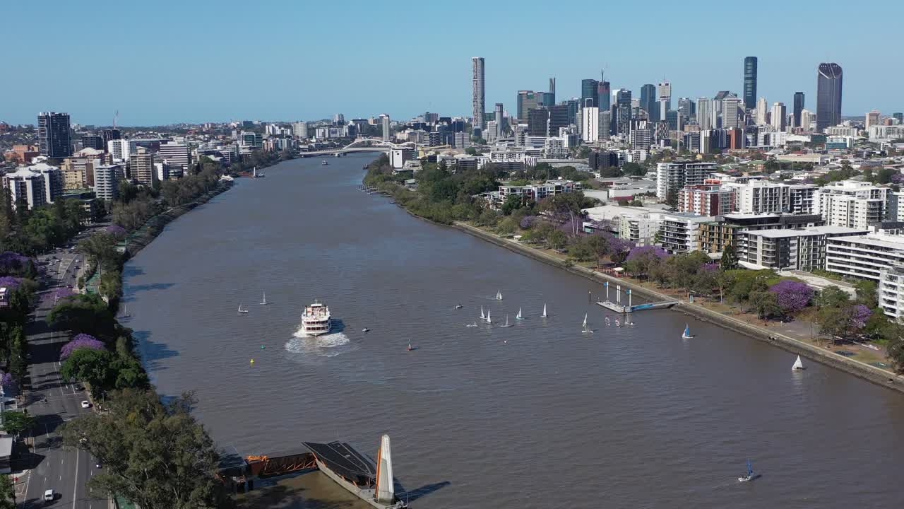 Drone shot tracking forwards revealing many small boats having a sailing race on the Brisbane River, near West End and Toowong