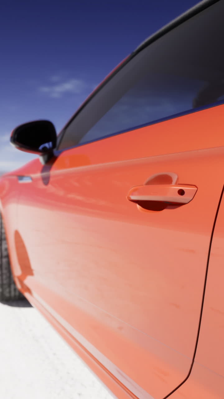 Bright orange car on expansive white salt flat under blue sky