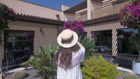 woman in straw hat taking photos in a tropical garden