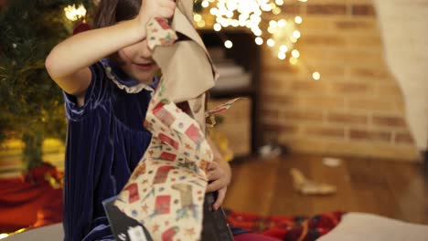 Hübsches-Mädchen-Im-Kleid,-Das-Weihnachtsgeschenke-Auf-Dem-Boden-Auspackt
