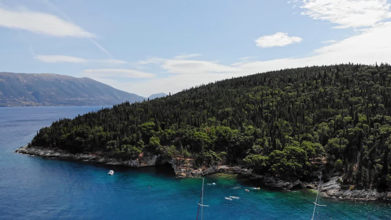Tourists Swimming In Emerald Crystal Water Of Foki Beach In Kefalonia Island, Greece With Densely Forested Hill