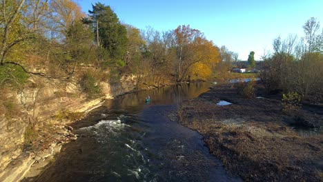 Aerial-shot-flying-backward-while-person-in-canoe-enters-rapids