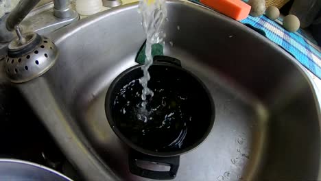 cámara lenta - agua corriendo de un grifo a una olla en el fregadero de la cocina