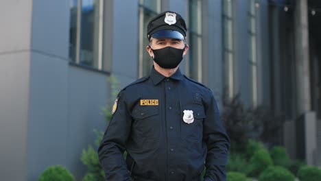 policía senior caucásico con máscara facial y uniforme mirando la cámara en la calle