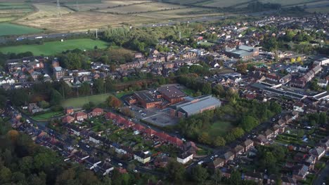 Lush-green-British-suburb-neighbourhood-alongside-M56-motorway-aerial-zoom-in