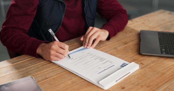 Man Signing a Financial Agreement Document at a Desk